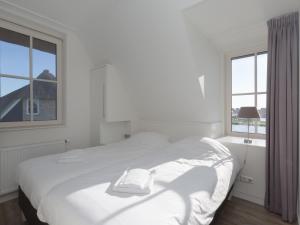 una camera bianca con un letto e una finestra di Beautiful villa with wellness in a holiday park on the Tjeukemeer a Delfstrahuizen