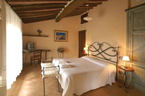 a bedroom with a white bed and a table at Podere Santa Maria in Monte Antico