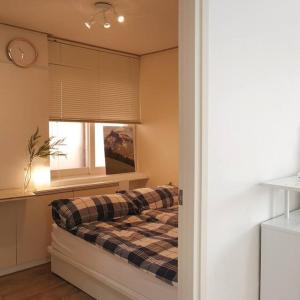 1 dormitorio con cama y ventana en [ COM,A stay] Hongdea St 5min / 3room, en Seúl