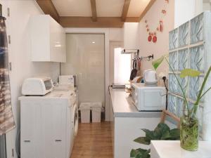 cocina con armarios blancos, lavadora y secadora en [ COM,A stay] Hongdea St 5min / 3room, en Seúl