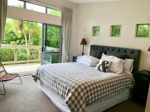 a bedroom with a bed and a large window at Ribbonwood Treetops cottage in Havelock North