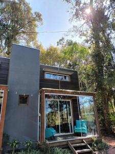 a house with a glass door and two blue chairs at Tiny House II - Sítio dos Wolff in Gravataí