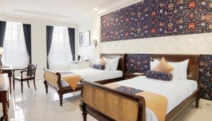 梭羅的住宿－MAHALAYA The Legacy Hotel，酒店客房设有两张床和一张桌子。