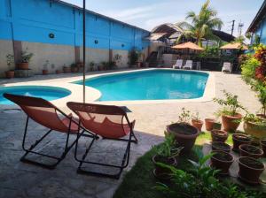 una piscina con 2 sillas y macetas en Hotel Virrey Pucallpa EIRL en Pucallpa