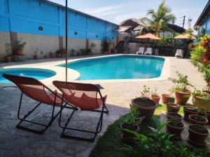 a swimming pool with two chairs and potted plants at El Virrey Hospedaje in Pucallpa +40 photos