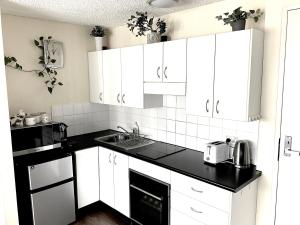 uma cozinha com armários brancos e um balcão preto em Namely Manly em Sidney
