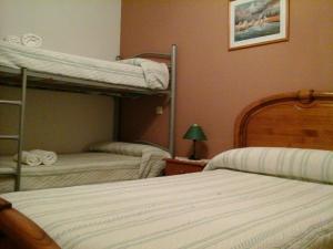 a bedroom with two bunk beds and a table with a lamp at Hostal Piñera in Vega de Espinareda