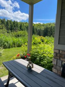 a picnic table on a porch with a view of a garden at Dida in Saint-Sauveur-des-Monts