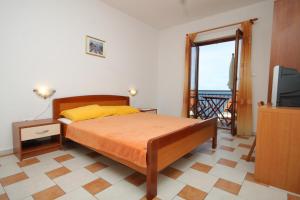 a bedroom with a bed and a television and a balcony at Apartments by the sea Milna, Hvar - 8795 in Hvar