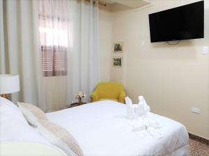 a bedroom with a white bed and a television at El Virrey Hospedaje in Pucallpa