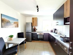 cocina con armarios negros, mesa y comedor en Stilvolles Apartment mit Balkon, en Wilhelmshaven 32 fotos más