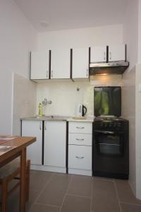 a kitchen with white cabinets and a black oven at Apartments by the sea Cavtat, Dubrovnik - 8826 in Cavtat