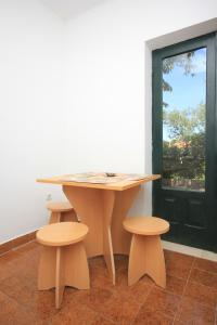 a wooden table with two stools next to a window at Apartments by the sea Cavtat, Dubrovnik - 8827 in Cavtat