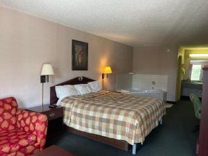 Habitación de hotel con cama y silla en Red Carpet Inn Macon East, en Macon