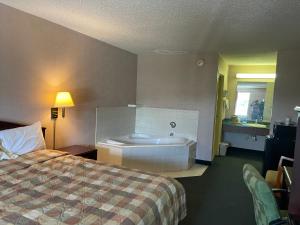 a hotel room with a bed and a bath tub at Red Carpet Inn Macon East in Macon