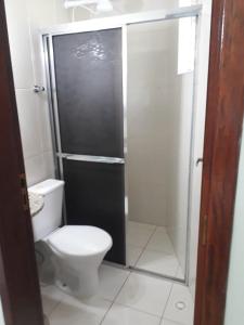ein Badezimmer mit Toilette und Glasdusche in der Unterkunft GUARUJÁ ENSEADA CASA 6 PES PROX PRAIA in Guarujá