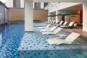 una piscina con sillones blancos y suelo de baldosa azul en Holiday Inn Cebu City, an IHG Hotel en Cebú