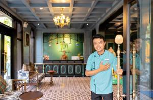 Un uomo in piedi di fronte a una stanza di Son Hoi An Boutique Hotel & Spa a Hoi An