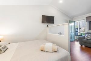 a white bedroom with a bed and a tv on the wall at Aspen Karratha Village in Karratha