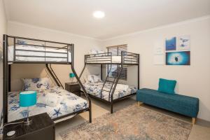 a bedroom with two bunk beds and a chair at Eclipse Absolute Beachfront with Stunning Views in Culburra Beach