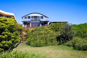 een groot huis bovenop een heuvel met struiken bij Eclipse Absolute Beachfront with Stunning Views in Culburra Beach