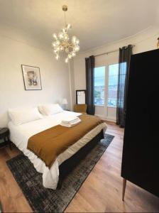 a bedroom with a large bed and a chandelier at Vichy : Le 5e - Appartement design dans un ancien palace in Vichy