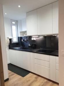 a kitchen with white cabinets and black counter tops at Vichy : Le 5e - Appartement design dans un ancien palace in Vichy