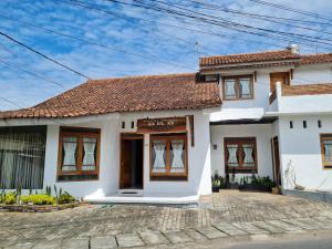 een wit huis met een rood dak bij BRB Guesthouse in Banyuwangi