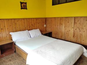 a bedroom with a white bed with a yellow wall at Hotel Mhelung in Darjeeling