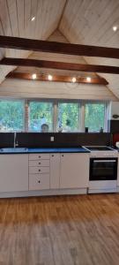 a large kitchen with white cabinets and windows at The parrot hotel, live in a rescue animal park in Næstved
