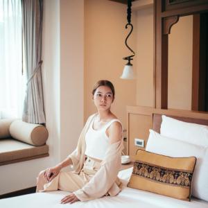 uma mulher sentada numa cama num quarto de hotel em Maraya Hotel & Resort -SHA Plus em Chiang Mai