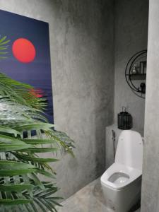 a bathroom with a toilet and a painting on the wall at Sunset resorts and bar in Ban Nong Chaeng