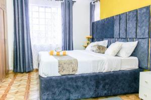 a bedroom with a large bed with a blue headboard at The GEM - Kiambu road Best 2Bedroom apartment in Nairobi