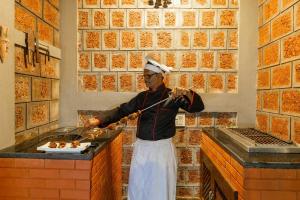 un hombre cocinando comida en una parrilla en una cocina en StayVista at The Haven - Grandeur with Breakfast & BBQ Grill, en Madikeri