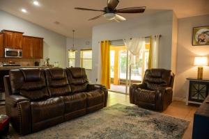 een woonkamer met 2 leren stoelen en een plafondventilator bij Charming vacation home in Port St Lucie. in Port Saint Lucie
