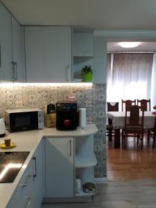 a kitchen with white cabinets and a dining room at Садиба у Насті in Nizhniy Studenyy