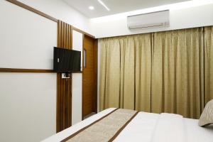 a hotel room with a bed and a tv at Tulsi Hotel in Surat
