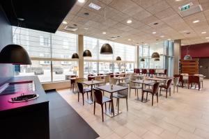 a restaurant with tables and chairs and windows at Campanile La Roche Sur Yon Centre Gare in La Roche-sur-Yon