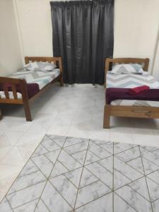 two beds in a room with a tiled floor at CiTY Roomstay Budget Midtown Kuala Terengganu 2queen beds in Kuala Terengganu