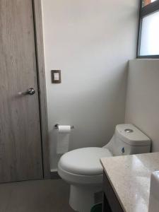 La salle de bains blanche est pourvue de toilettes et d'une fenêtre. dans l'établissement Beautiful 3BR townhouse with on-premises parking, à Calimaya de Díaz González