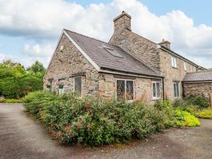 an old stone house with flowers in front of it at Yr Hen Efail in Welshpool