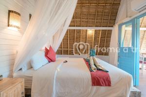 a bedroom with a bed with a mosquito net at Dream Beach Kubu & SPA by ABM in Nusa Lembongan