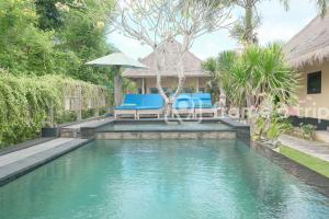 a swimming pool with two blue chairs and an umbrella at Dream Beach Kubu & SPA by ABM in Nusa Lembongan