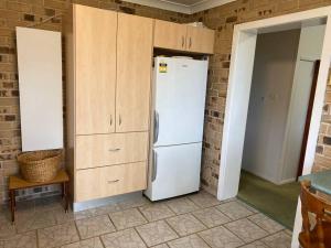 a kitchen with a white refrigerator and wooden cabinets at Crescent Head - Killick Glen - a couple's retreat in Crescent Head