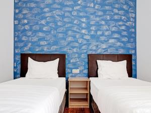 two beds in a room with a blue wall at OYO 89840 69 Room 4 Stay in Sibu