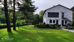 a white house with a green yard at Lővér Vendégház Sopron in Sopron