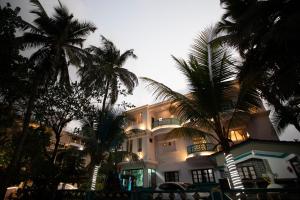 a large building with palm trees in front of it at TM Calangute House Stay at Goa in Calangute