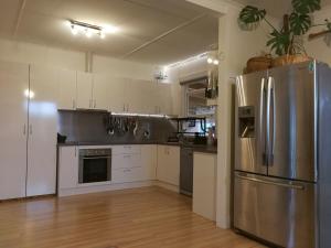uma cozinha com armários brancos e um frigorífico de aço inoxidável em Fun Family House King Island em Currie
