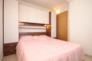 a bedroom with a large bed with pink sheets at Apartments by the sea Valun, Cres - 8086 in Valun