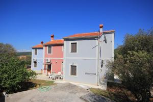 ein großes weißes Haus mit einem Tisch und Stühlen in der Unterkunft Apartments by the sea Ilovik, Losinj - 8075 in Ilovik